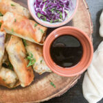 spring rolls on wooden serving try with dipping sauce