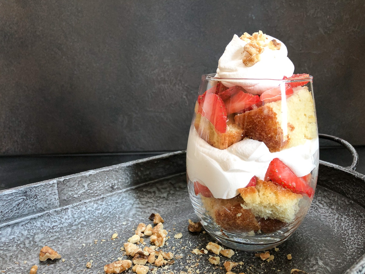 strawberry parfait on oval tray with crushed walnuts on tray.