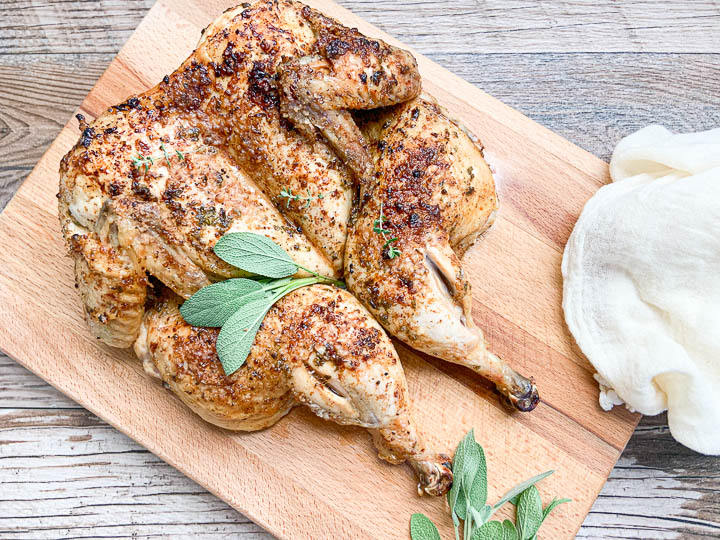 roasted chicken on cutting board garnished with fresh herbs 