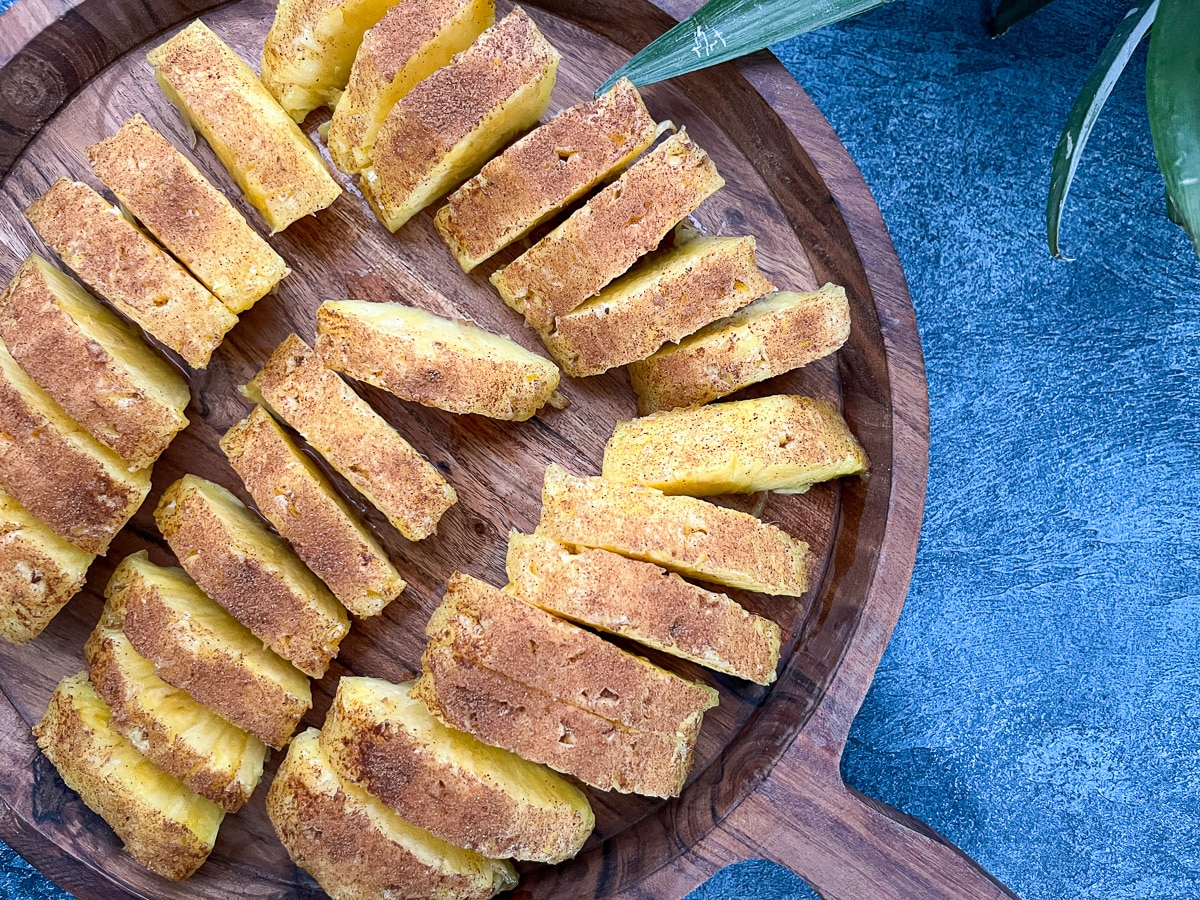 close-up of slices of brazilian pineapple on round wooden tray.