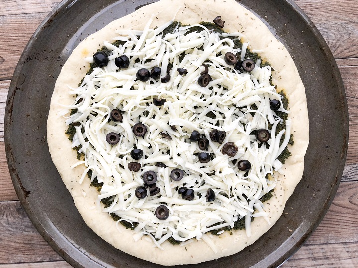 pre-baked pizza dough topped with pesto sauce, mozzarella cheese and olives