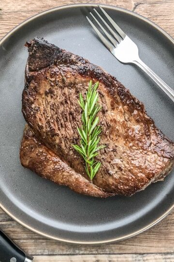 london broil that has been cooked in oven served on a bluish gray dinner plate