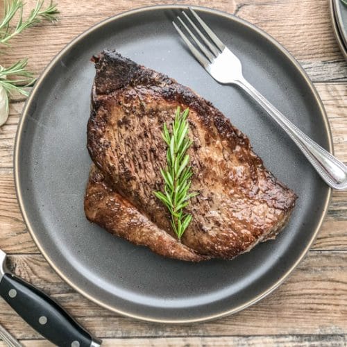 london broil that has been cooked in oven served on a bluish gray dinner plate