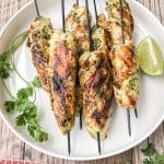 grilled cilantro lime chicken skewers served on a white plate with sliced lime