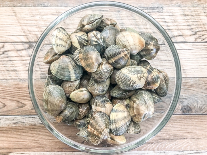 unopened live clams in glass bowl