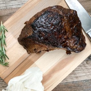 tri tip on wooden chopping board with knife and rosemary