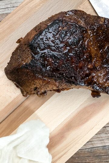 tri tip on wooden chopping board with knife and rosemary