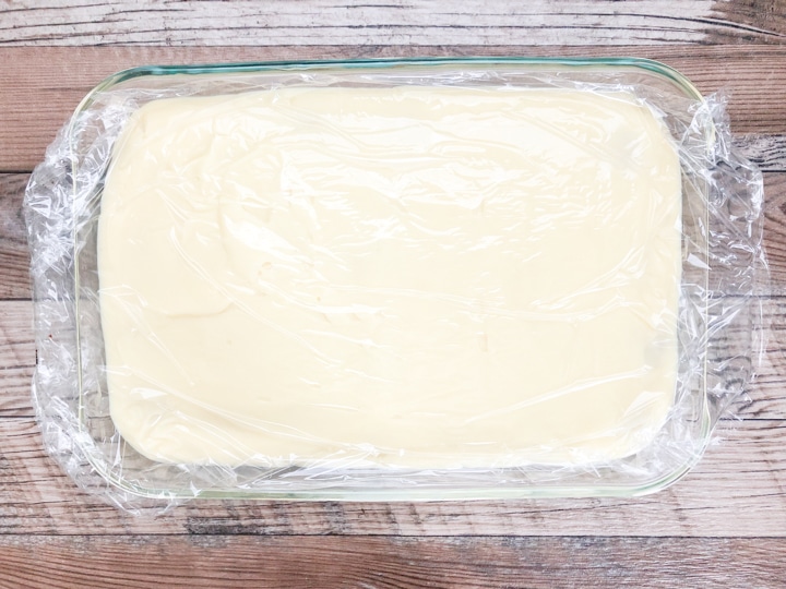 vanilla pudding in glass casserole dish with plastic wrap on top