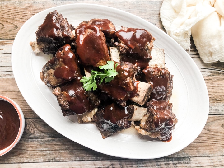 over head image of instant pot beef short ribs with bowl of bbq sauce