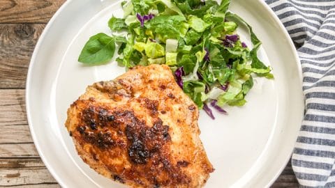 seared chicken breast on white plate with fresh green salad