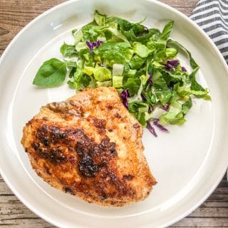 juicy chicken breast cooked in cast iron skillet served on white plate with salad