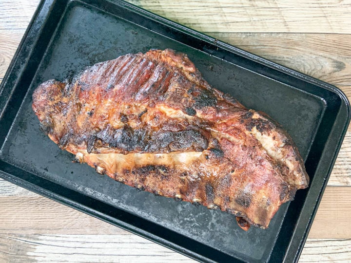 slab of grilled pork spare ribs on baking sheet