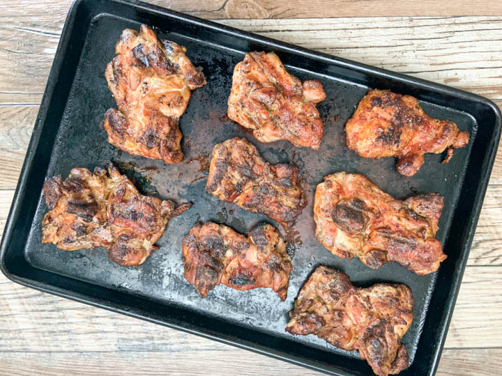 chicken thighs taken off grill and placed on baking sheet to rest