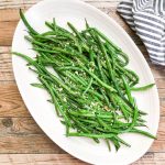 green beans served on a white platter topped with toasted panko crumbs