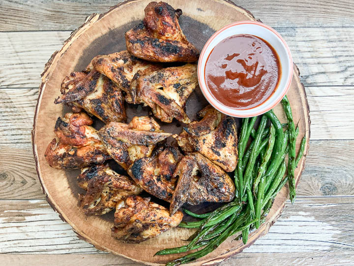 chicken wings on tray with small bowl of bbq sauce.