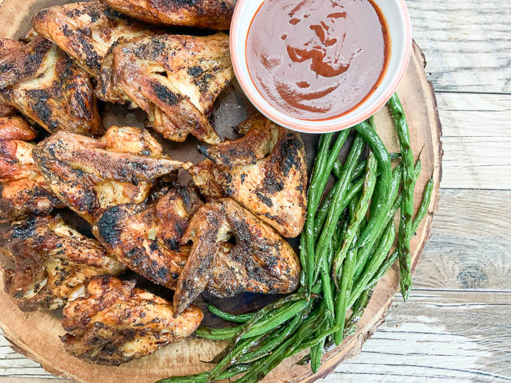 close up of grilled chicken wings on round wooden serving tray