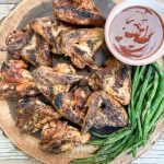 grilled chicken wings on round serving tray with grilled green beans