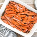 candied yams in white casserole dish next to gray striped napkin
