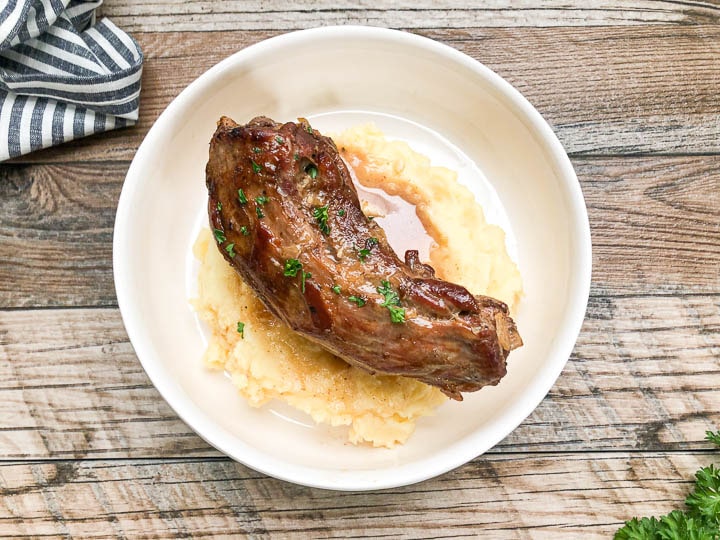 one turkey neck on top of mashed potatoes in white bowl