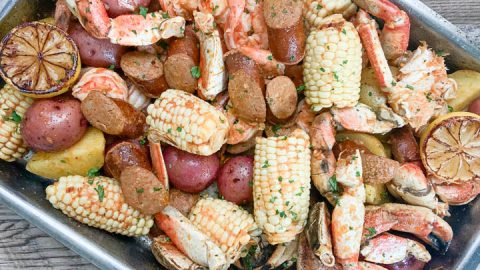 seafood boil in pan garnished with lemon lemon and parsley