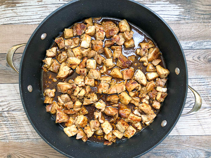 seared chicken thighs cut into cubes simmering in skillet