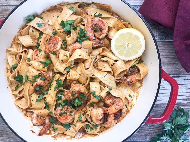 creamy Cajun shrimp pasta in red dutch oven with napkin on side