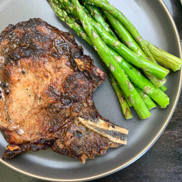 grilled ribeye on blue plate with grilled asparagus