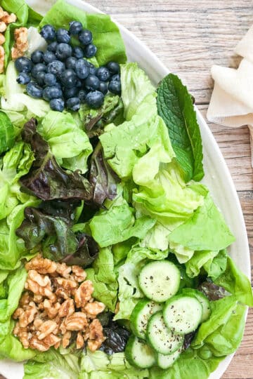 spring mix salad on platter with beige napkin next to platter