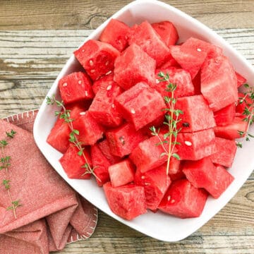 watermelon cut into cubes in white bowl with garnish