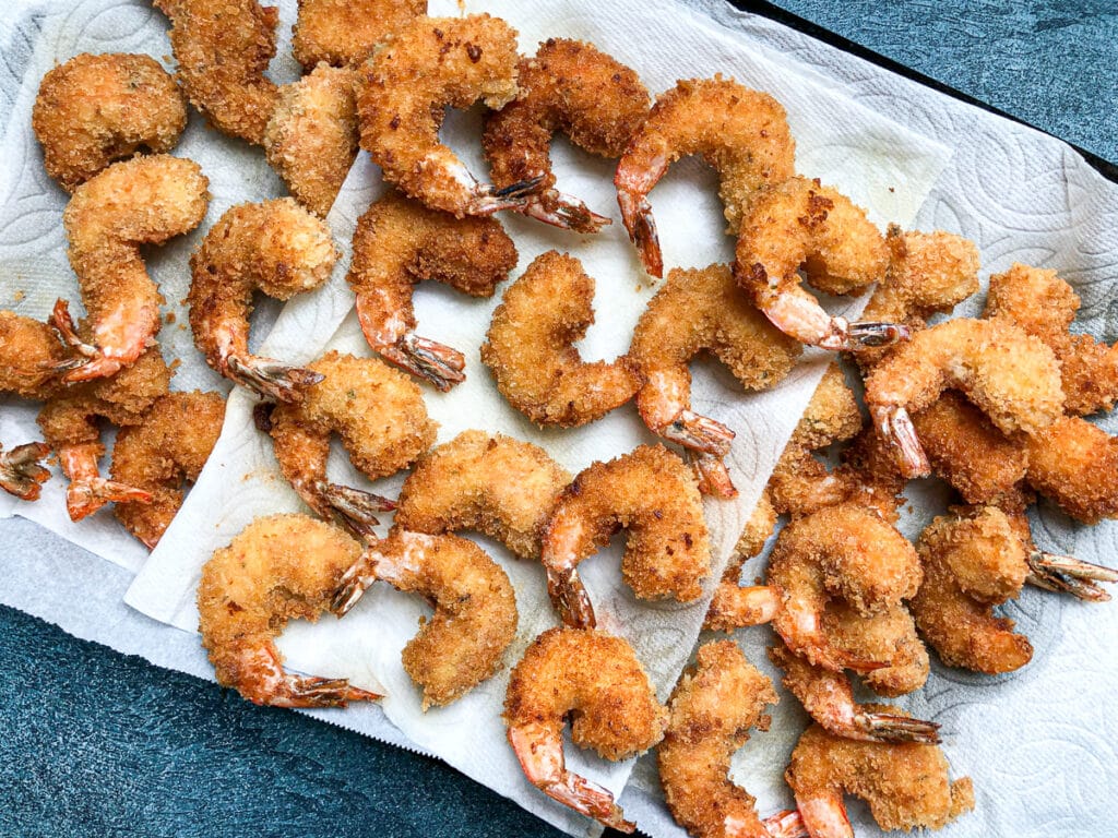 baking sheet lined with paper towels and panko fried shrimp on top.