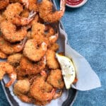 panko fried shrimp in oval platter with dipping sauce.