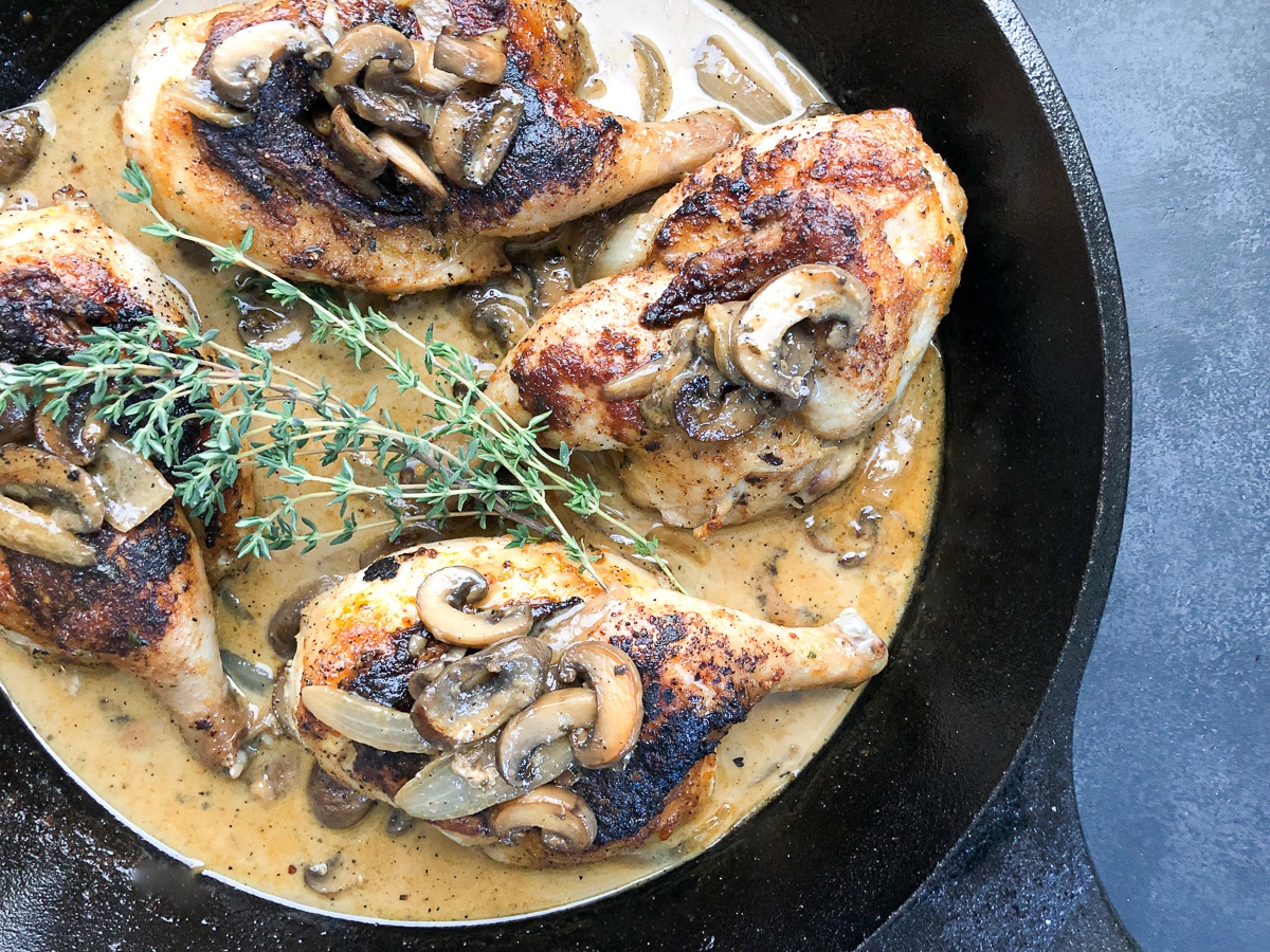 close-up of roasted cornish hens in white wine sauce topped with mushrooms