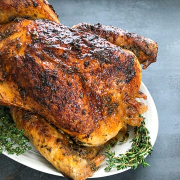 roasted turkey on white platter next to gray napkin.