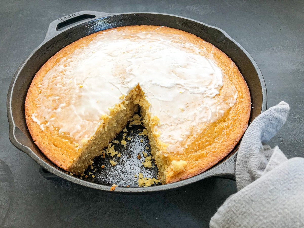 close-up of cake cornbread in skillet with slice cut out.