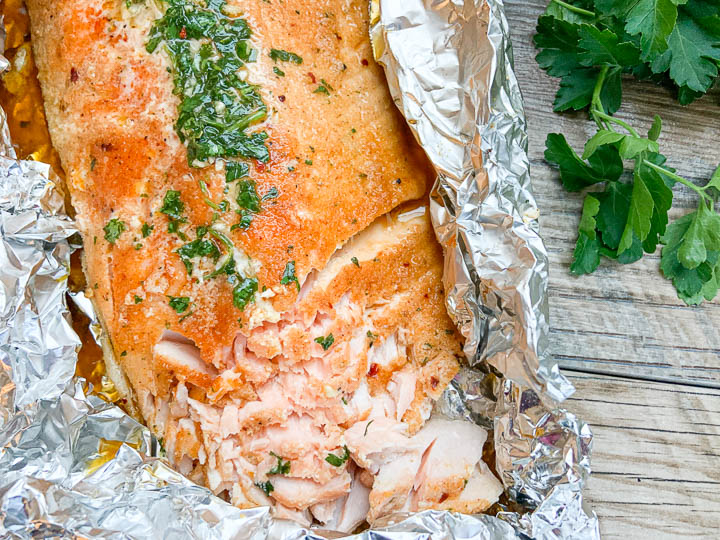 grilled salmon in foil that has been flaked with a fork.