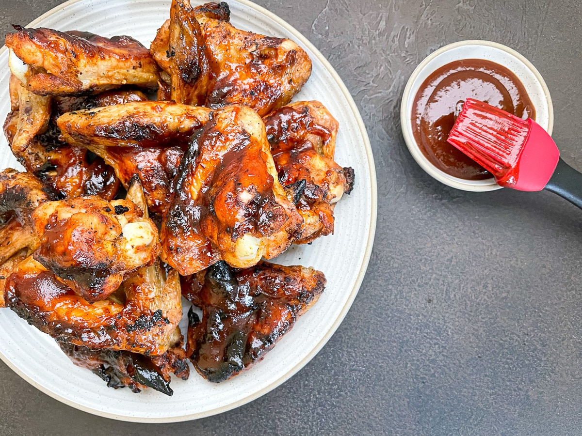 charcoal grilled chicken wings on round white plate.