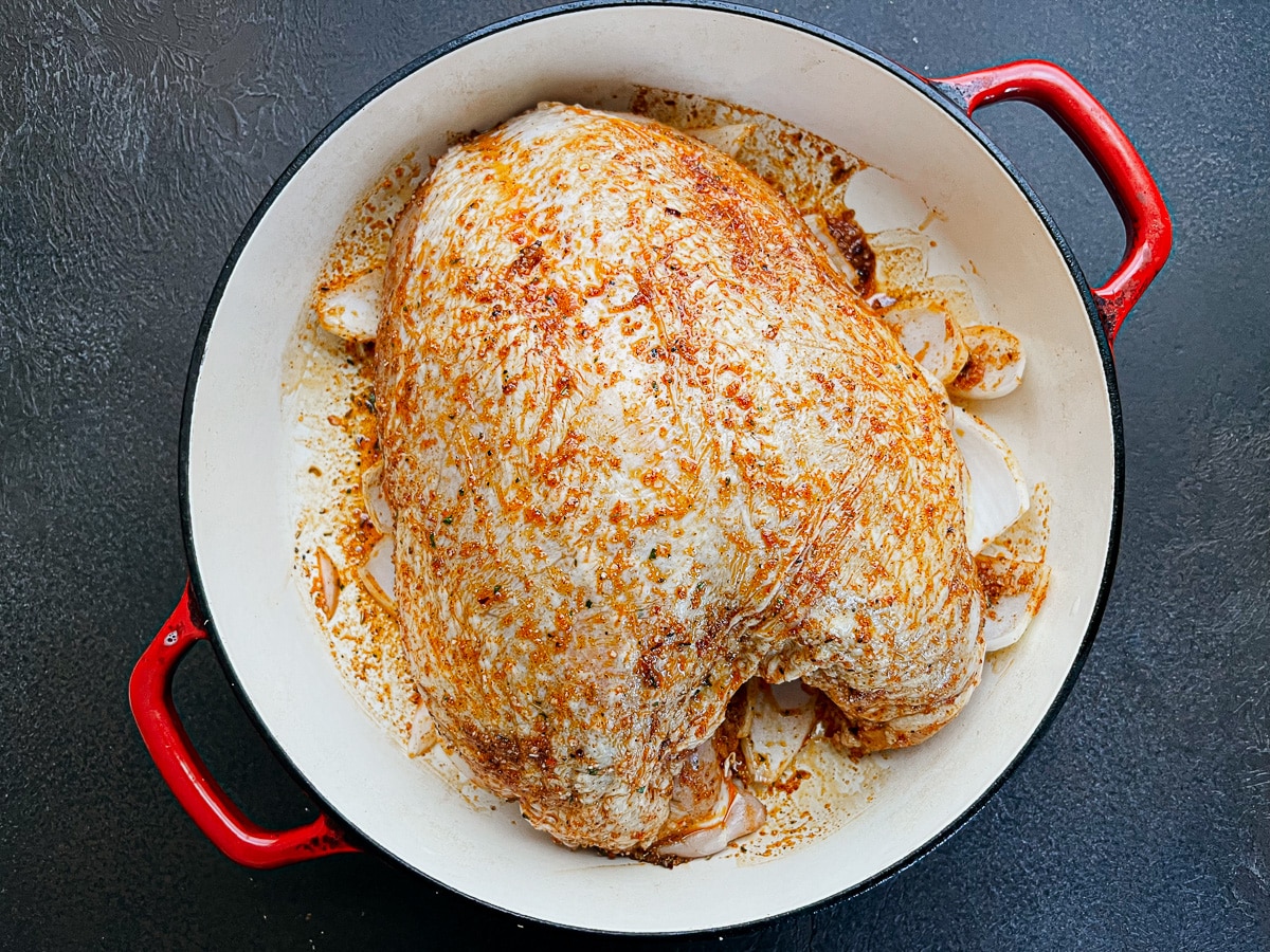 seasoned raw turkey breast in red dutch oven.