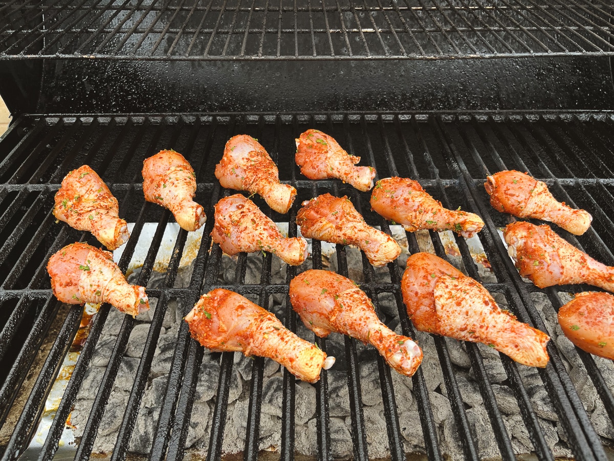 seasoned chicken legs on grill grates.