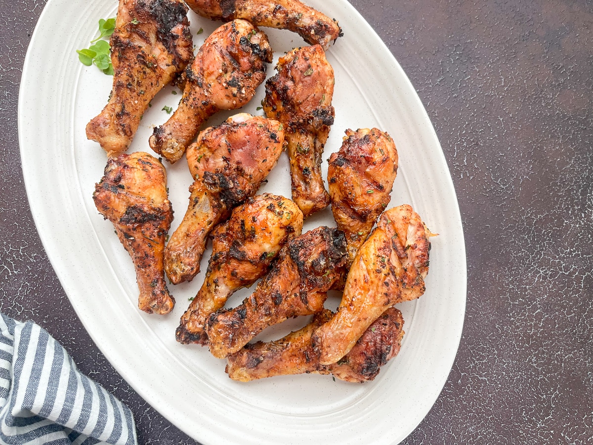 grilled chicken legs on white serving tray.