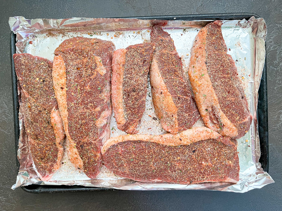 seasoned raw coulotte steak on lined baking dish.