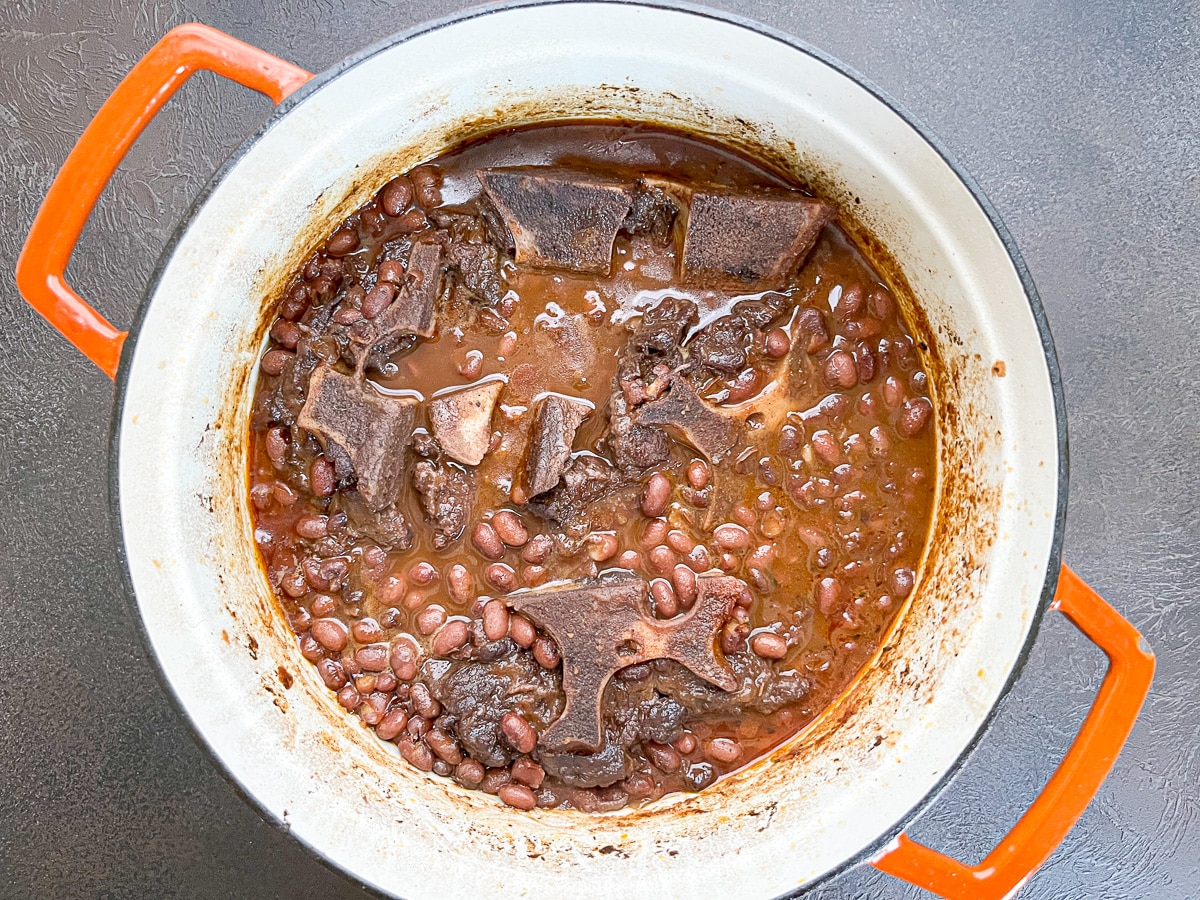 Cooked Cajun red beans inside of an orange Dutch oven.