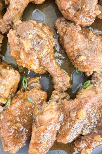 Close-up of saucy braised chicken wings on a gray dinner plate.