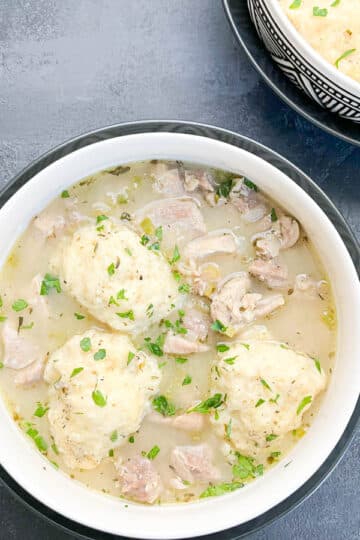 Two bowls of chicken and dumplings in decorative white bowls.