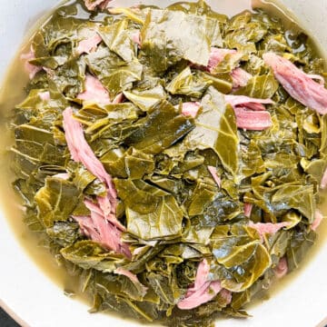 Tender collard and mustard greens in a white bowl with smoked shredded turkey.