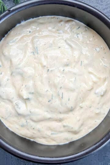 Creamy Cajun jalapeno tartar sauce with dill in a small black dipping bowl, ready to serve, next to fresh dill.