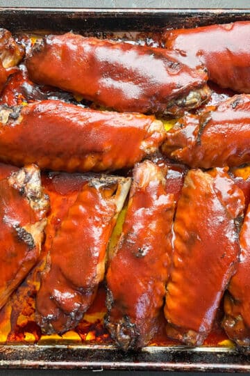 Overhead shot of barbecue turkey wings on a foil-lined baking sheet, ready to be served.
