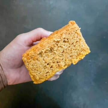 One fluffy slice of sweet potato cornbread held up to show its soft texture and crumb.
