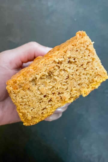 One fluffy slice of sweet potato cornbread held up to show its soft texture and crumb.