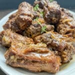 Frontal view of tender braised turkey necks arranged on a white serving platter.