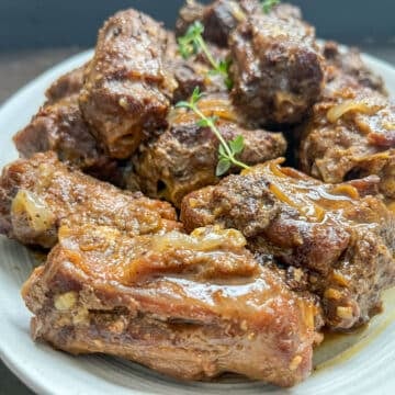 Frontal view of tender braised turkey necks arranged on a white serving platter.